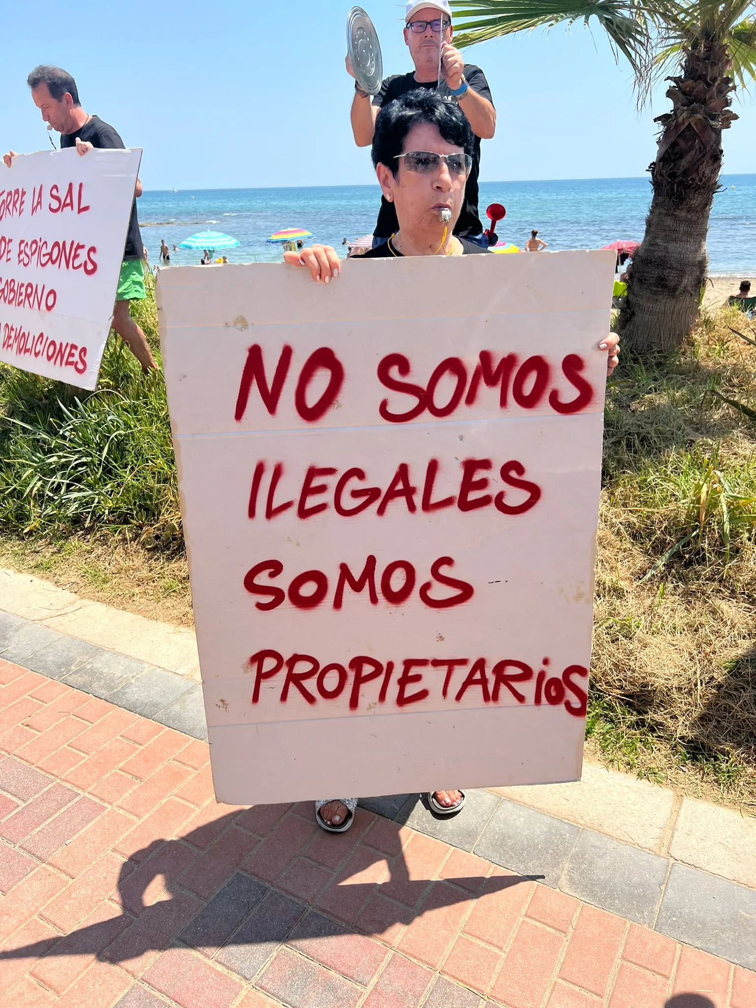 Bewohnerin von Torre la Sal mit einem Protestschild am Strand